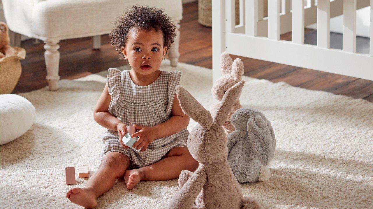 a baby sitting on a white rug with stuffed animals